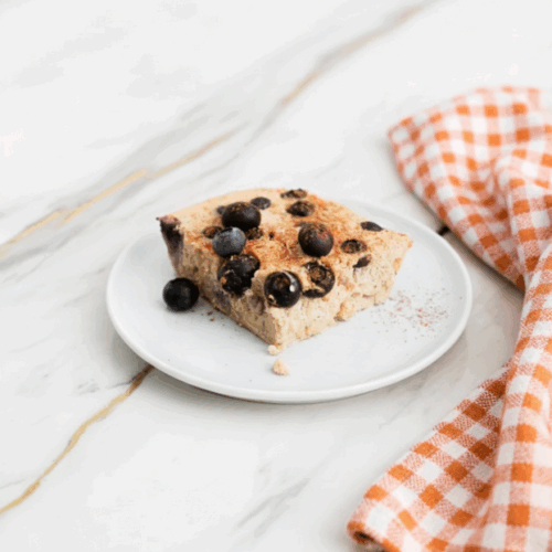 Blueberry cottage cheese breakfast bake with oats fresh from the oven in a ceramic dish with golden edges and bubbling fruit