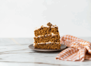 Carrot Cake with Candied Pecans topped with cream cheese frosting and caramelized pecan pieces on a white plate