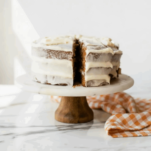 Carrot Cake with Candied Pecans topped with cream cheese frosting and caramelized pecan pieces on a white plate