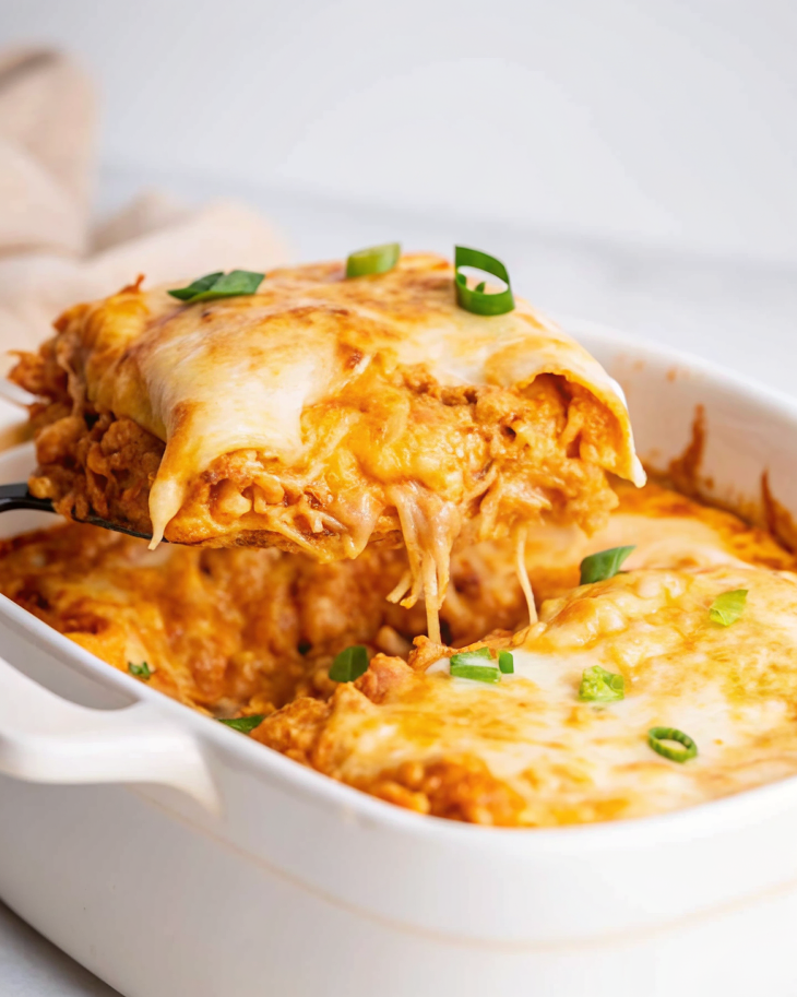 Chicken Enchilada Casserole with melted cheese, corn tortillas, and savory sauce in a baking dish