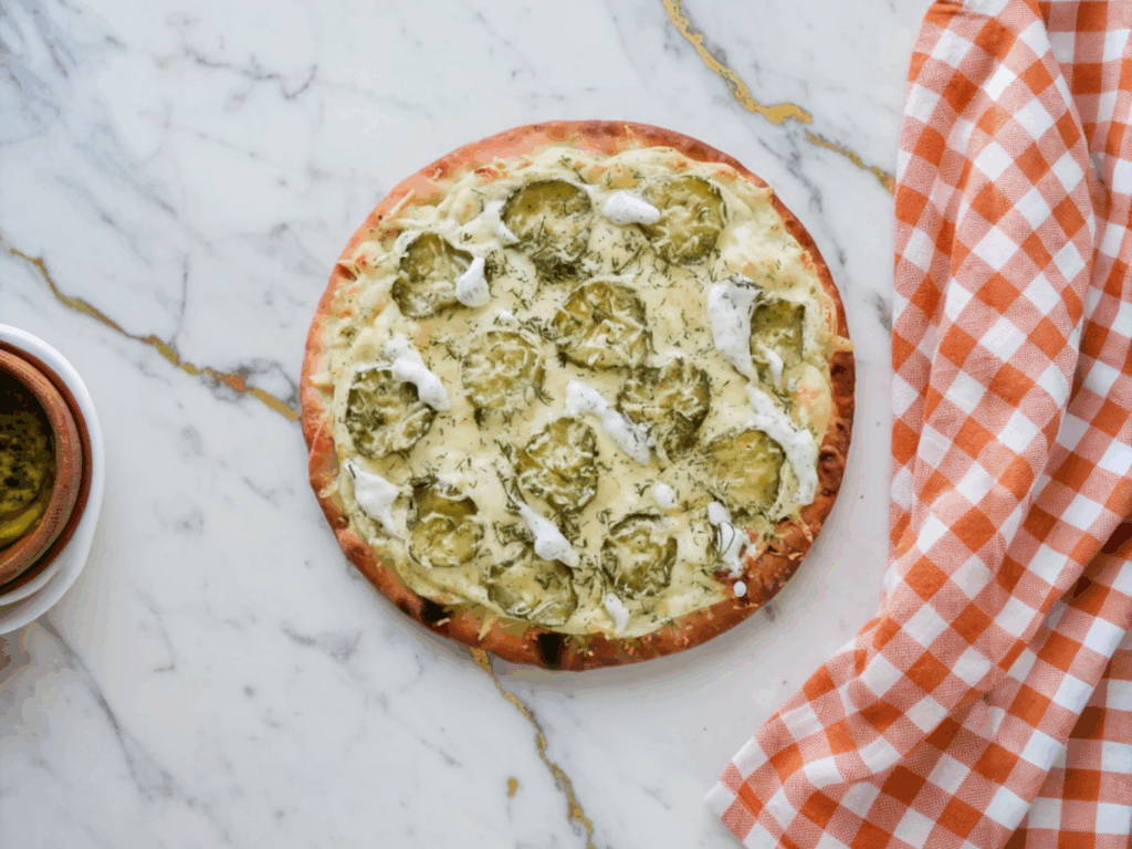 Dill Pickle Pizza topped with sliced pickles, melted mozzarella cheese, and fresh dill on golden crust