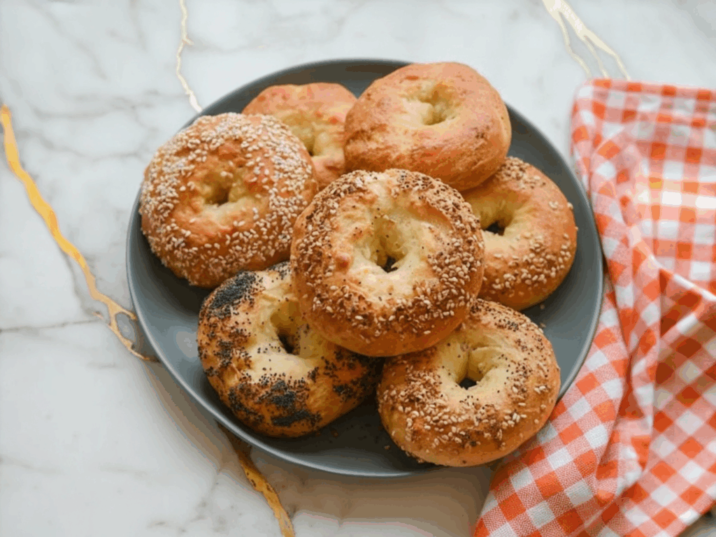 Freshly baked Greek Yogurt Bagels with golden brown crust arranged on a wooden board