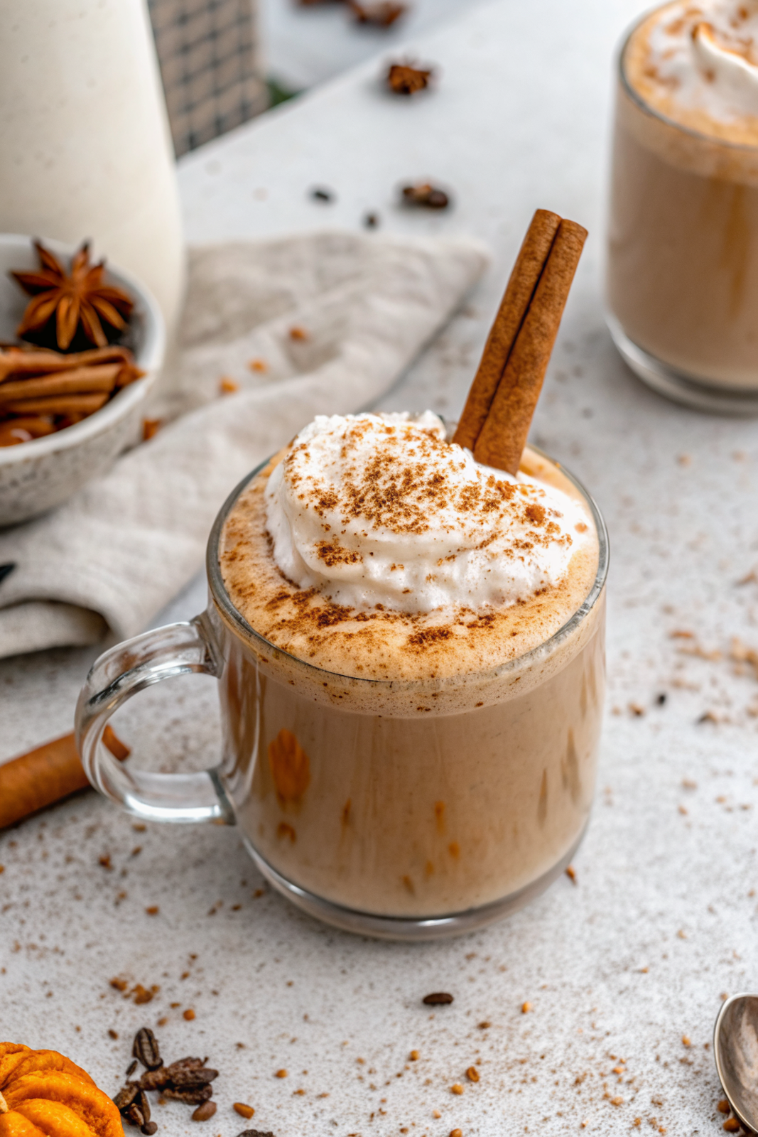 Homemade Pumpkin Spice Latte topped with whipped cream and cinnamon in a clear glass mug on a rustic wooden table