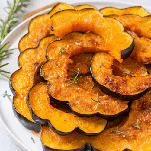 Maple Roasted Acorn Squash halves with caramelized glaze on white serving platter