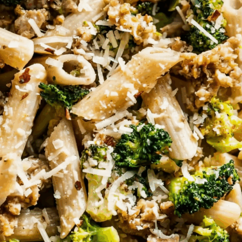 Sausage and Broccoli Pasta served in a white bowl with parmesan cheese and garlic sauce coating penne noodles