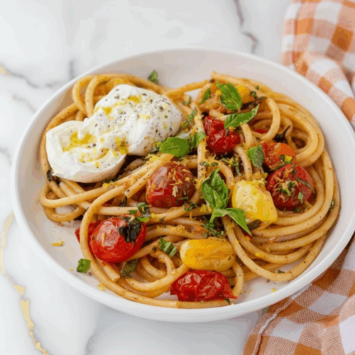 Tomato Basil Pasta served in white bowl garnished with fresh basil leaves and parmesan cheese