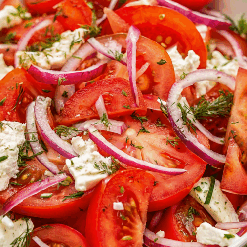 Tomato Salad with fresh cherry tomatoes, basil leaves, and dressing in a white bowl