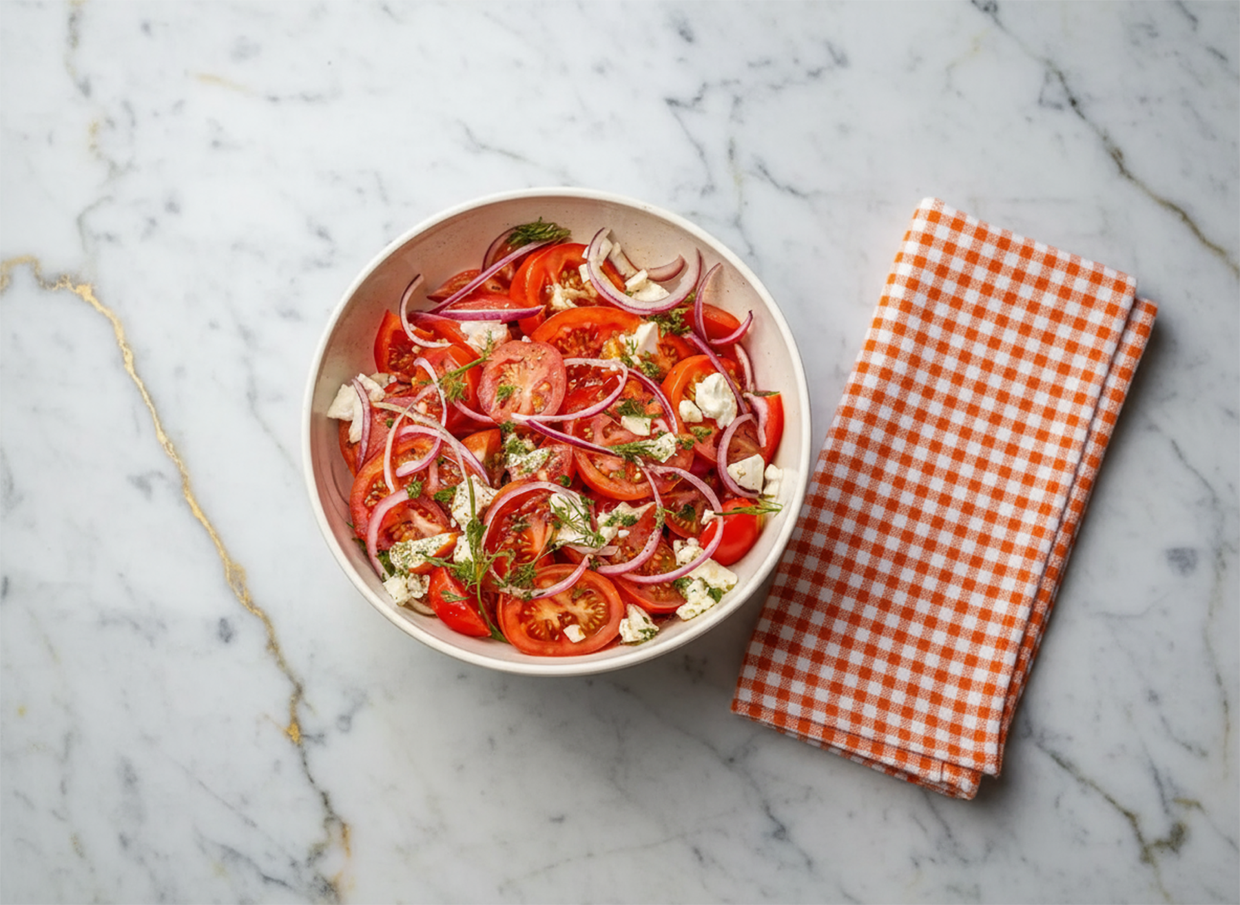 Tomato Salad with fresh cherry tomatoes, basil leaves, and dressing in a white bowl