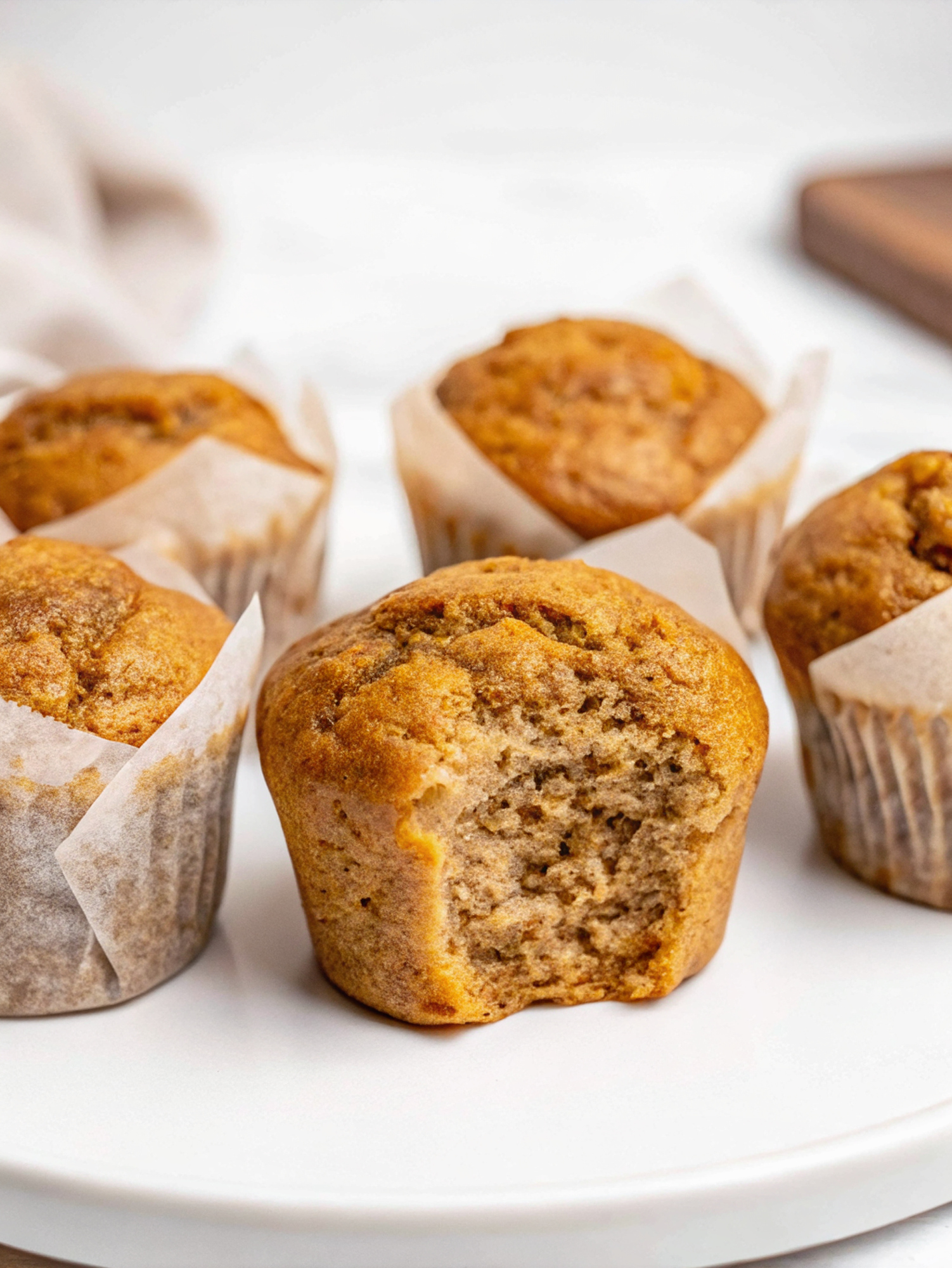 Banana Cottage Cheese Muffins with golden tops arranged on a white plate with fresh banana slices