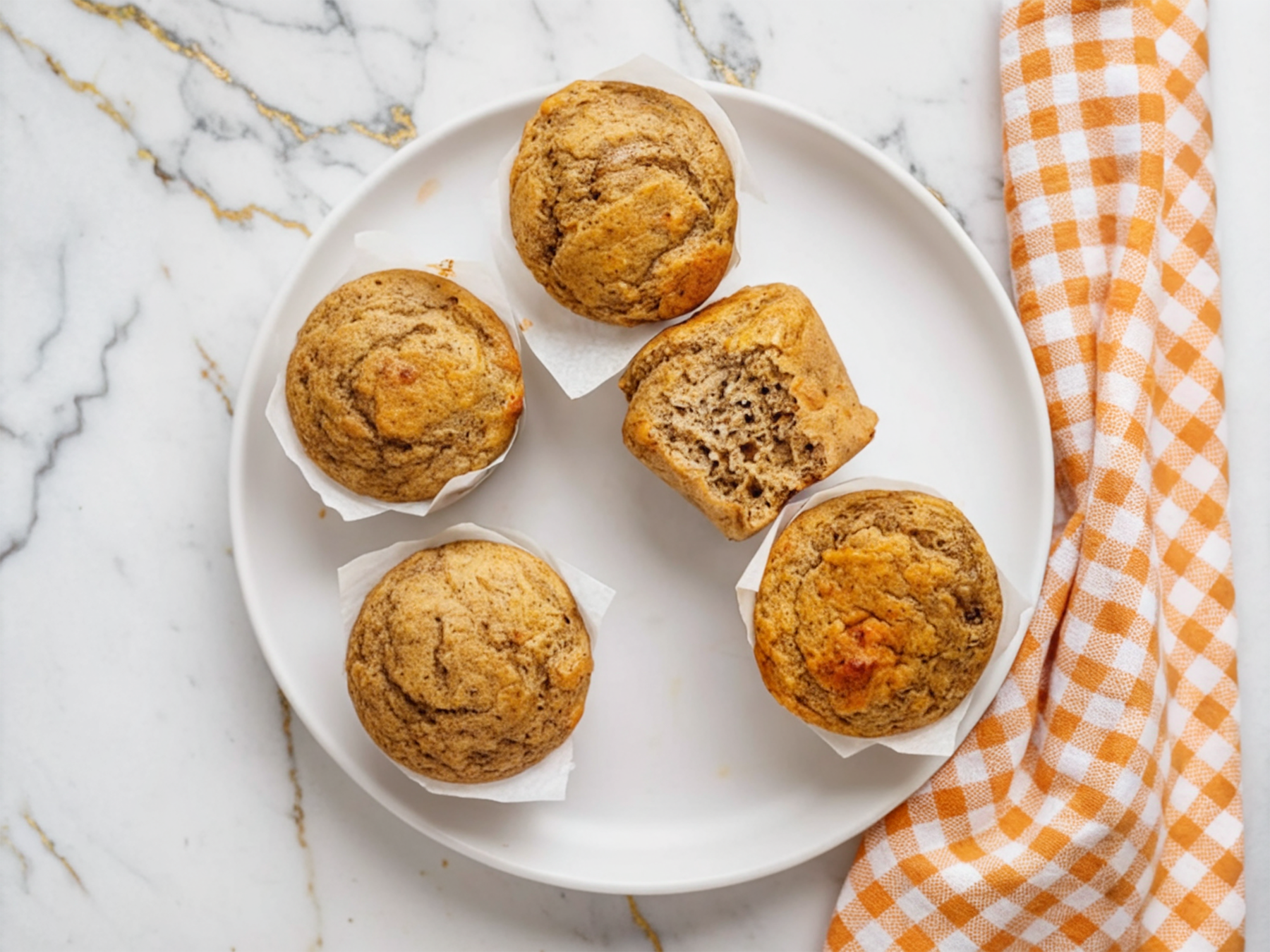 Banana Cottage Cheese Muffins with golden tops arranged on a white plate with fresh banana slices