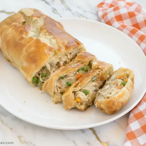 Golden brown chicken pot pie stromboli sliced on wooden board showing creamy filling with vegetables and tender chicken